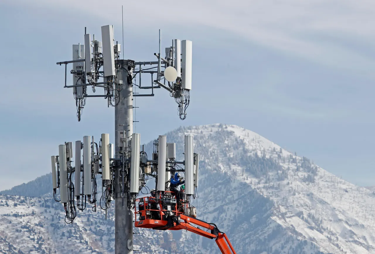 A cell tower against the sky with a Starlink satellite constellation illustrated above it.