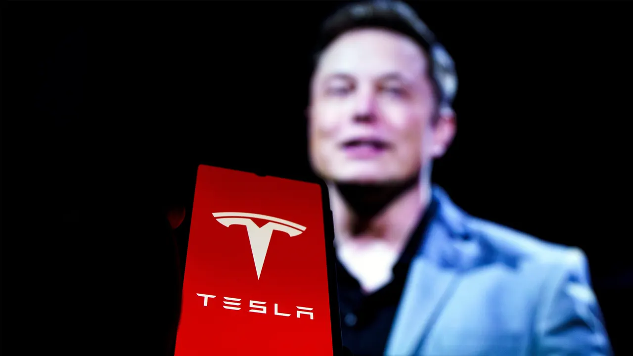 Tesla Optimus humanoid robot standing next to a Cybercab two-seat robotaxi without steering wheel or pedals.