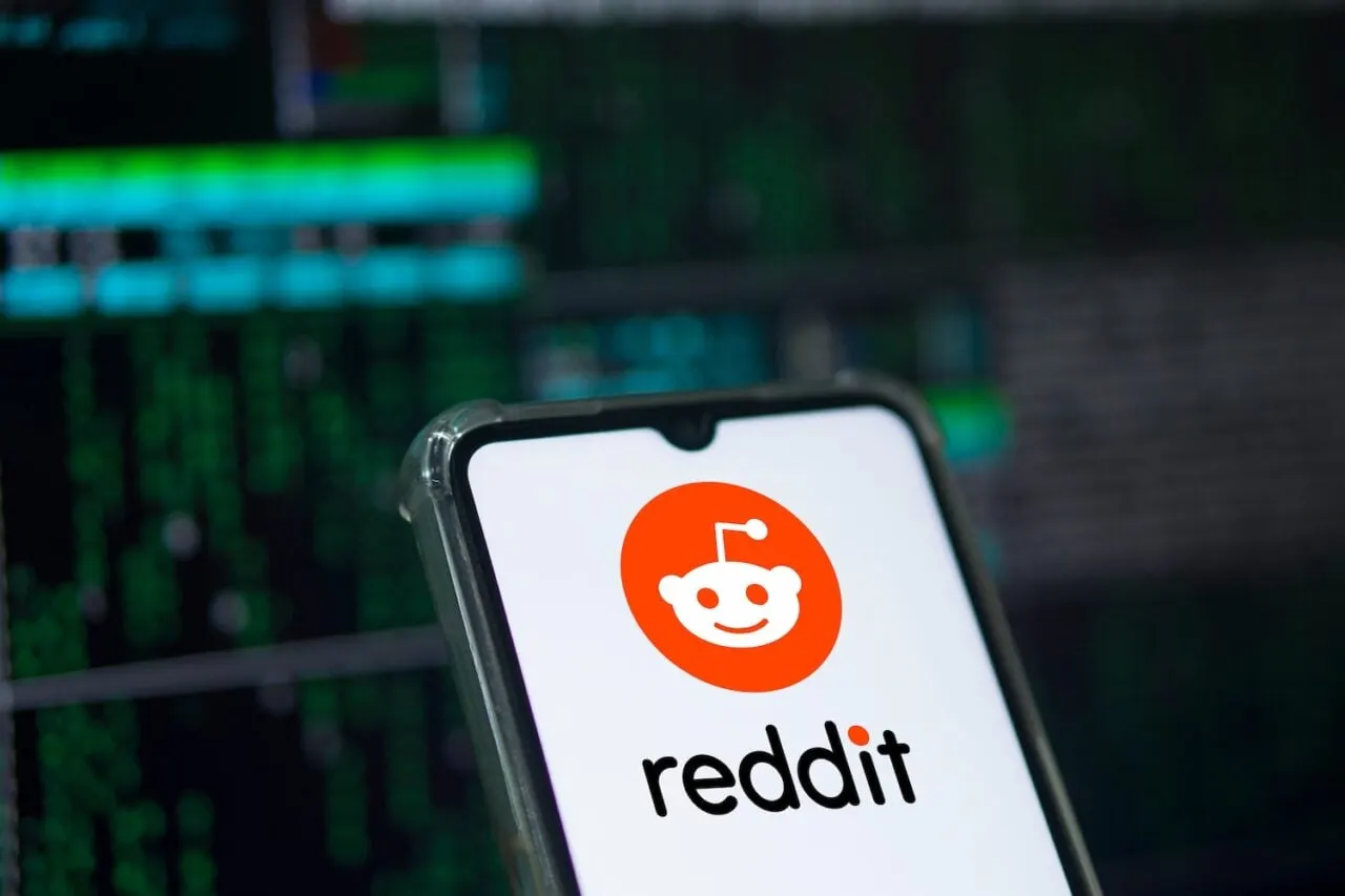 A laptop showing a Reddit community page next to open source code on a developer's desk.