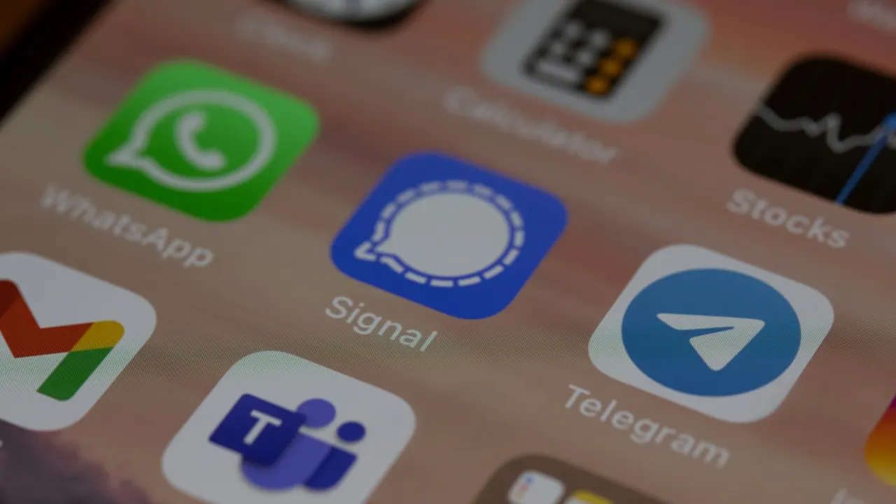 Smartphone showing a messaging app in front of a blurred office building, symbolizing an internal leak investigation at an AI company.