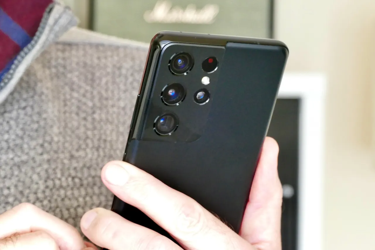 A Samsung Galaxy smartphone running a mobile game, with a heat and performance graphic in the background.