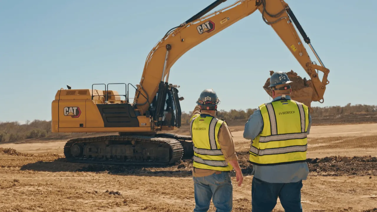 An autonomous excavator digging at a construction site, representing Bedrock Robotics' self-operating heavy machinery.