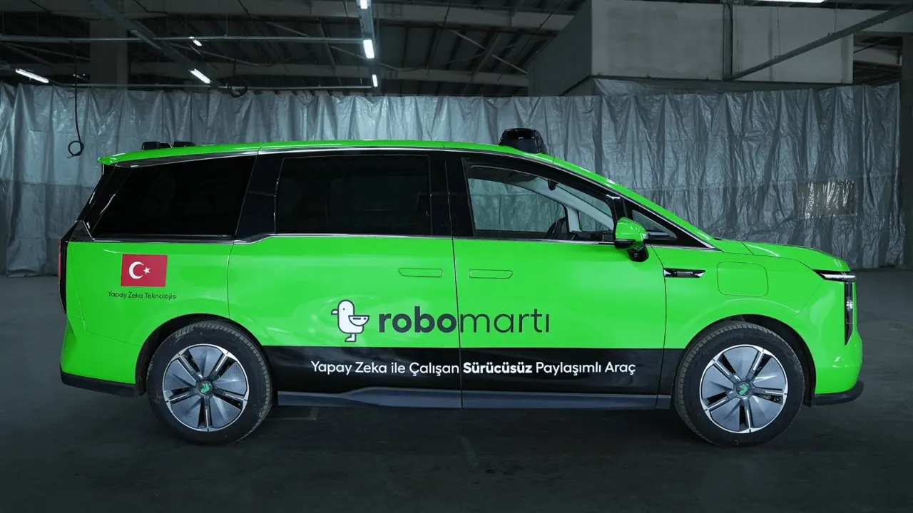 A self-driving shared-ride vehicle equipped with cameras, lidar and radar sensors driving on a city street.