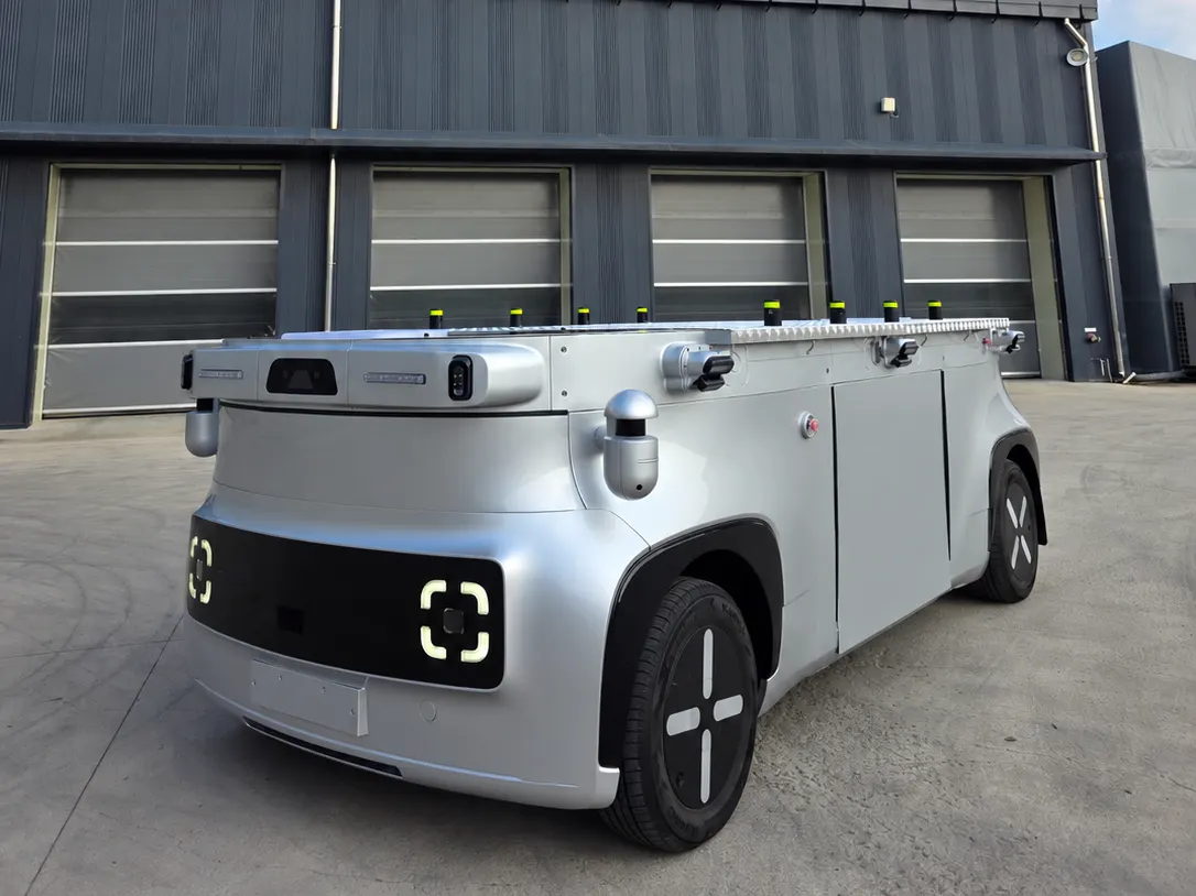 A driverless flat-bed autonomous cargo vehicle carrying industrial parts inside a factory.