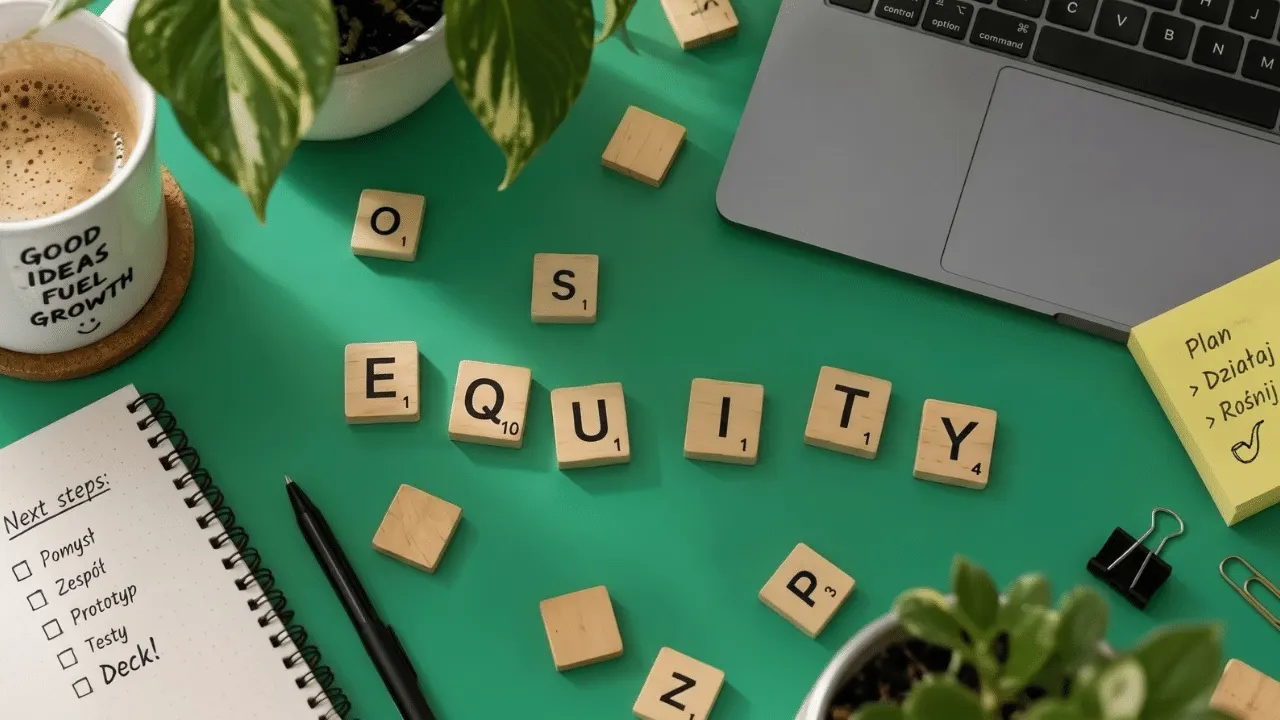 Two startup founders reviewing a capitalization table showing share allocation on a laptop screen.