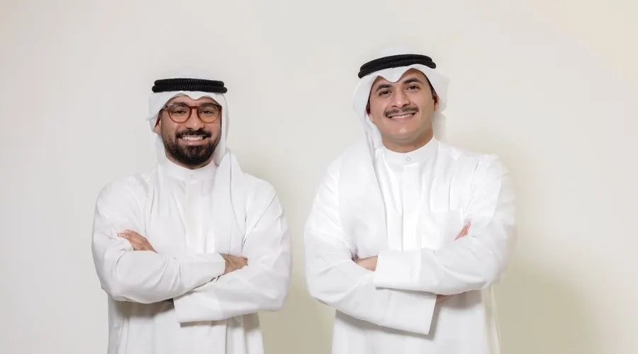Two startup founders in Kuwait reviewing consumer survey results on a laptop dashboard.