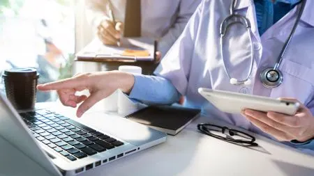 A doctor using a tablet to view a digital patient record in a clinic.