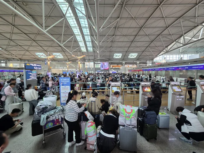 Passengers queue at airline check-in counters in a terminal at Incheon International Airport during a network outage.