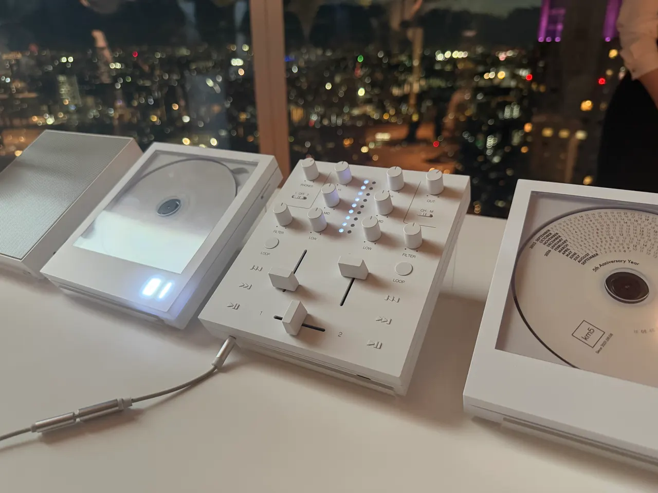 Slim square km5 Sp1 Bluetooth speaker beside the Mp1 wireless DJ mixer and two Cp1 CD players arranged as a compact DJ deck.