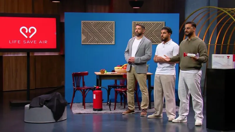 Three founders demonstrate a handheld suction mask device on a training dummy in front of investors in a television studio.