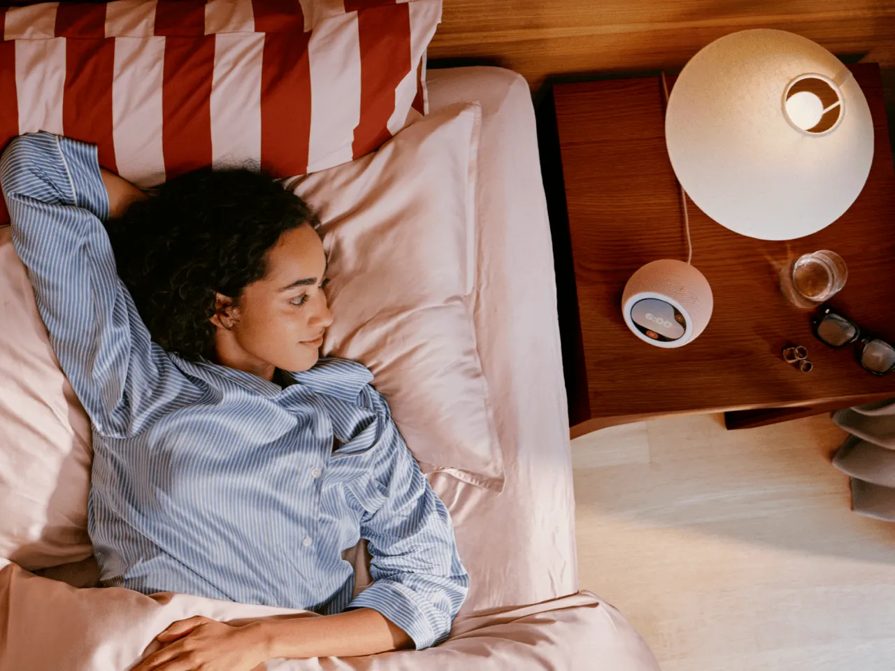 Amazon Echo Time smart alarm clock with a round touchscreen glowing like a sunrise on a bedside table.