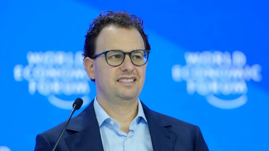 Anthropic CEO Dario Amodei in front of a stock exchange display, symbolizing the company's planned IPO.