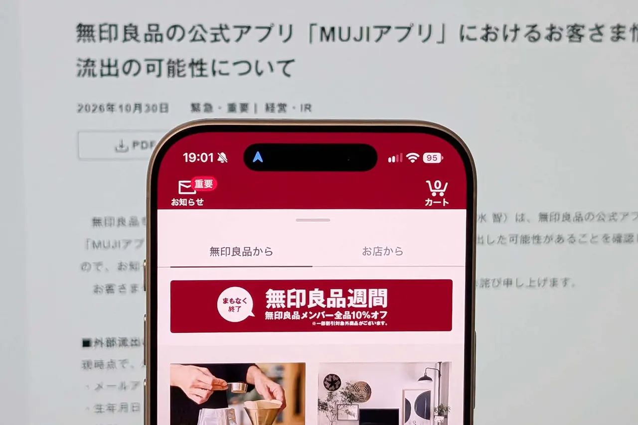 Smartphone showing a retail shopping app with a warning symbol, representing a customer data leak at Muji.