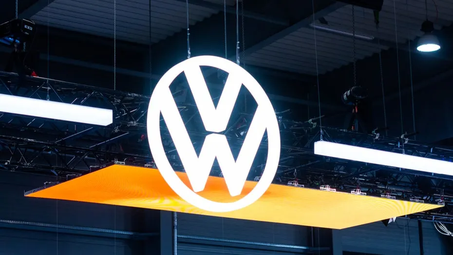 Volkswagen logo on a building at the company's Wolfsburg headquarters with electric ID models in the foreground.