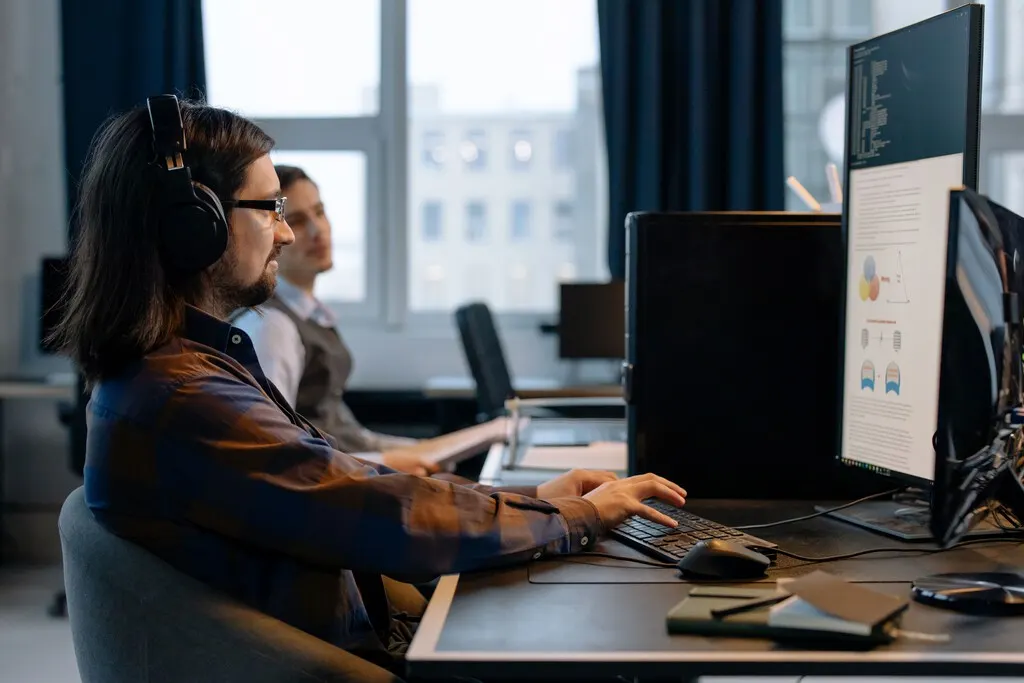 Software developer working at a desk with code on screen, symbolizing AI's growing impact on tech jobs in Spain.