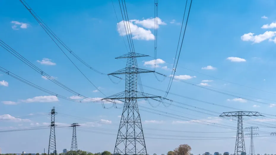 Large grid transformer at an electrical substation with power lines against the evening sky.