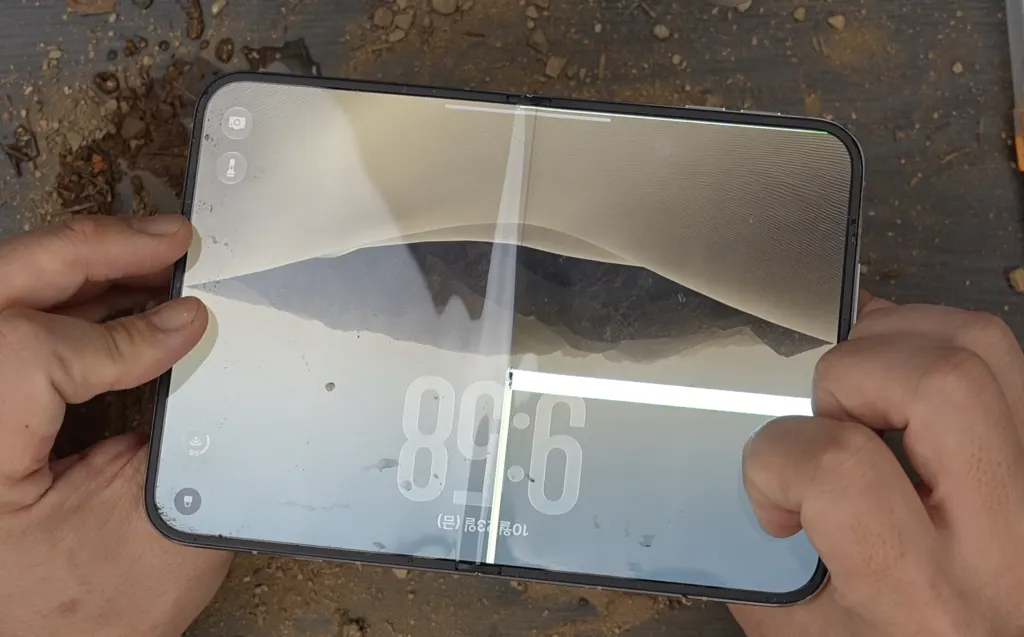 A foldable iPhone Duo with a broken inner display showing a horizontal line of dead pixels near the hinge.