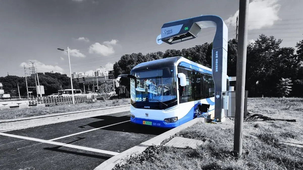 Electric autonomous minibus driving through a city intersection equipped with roadside cameras connected via 5G.