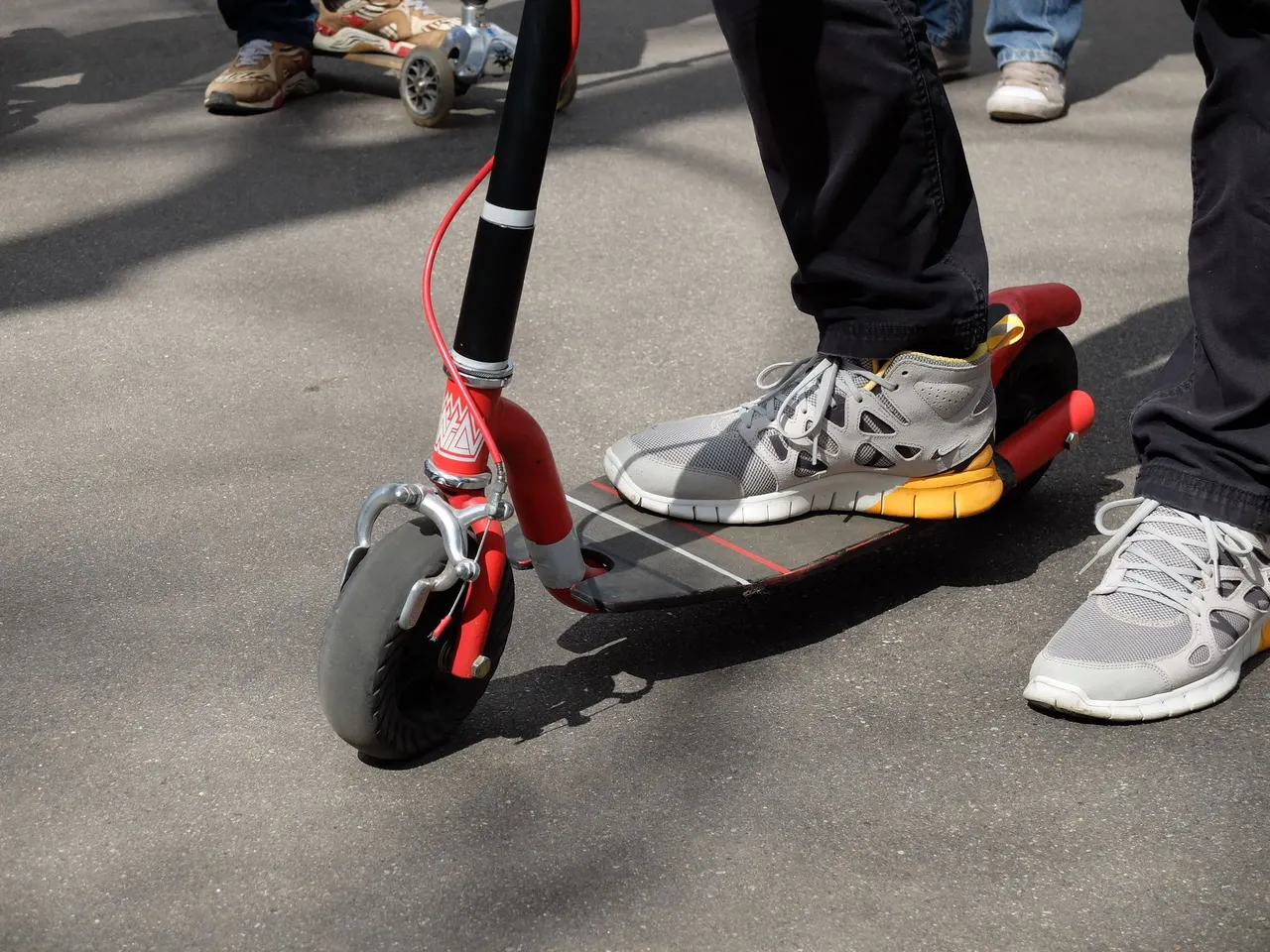 A person riding an electric scooter along a city street among pedestrians.