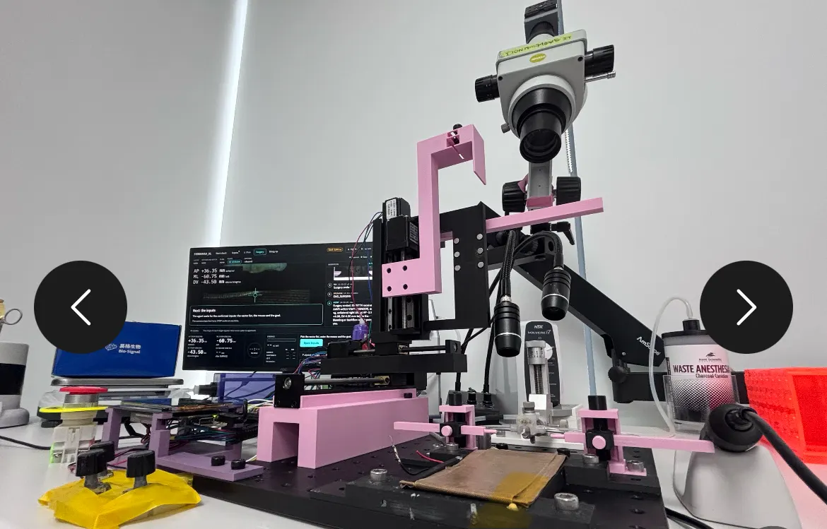 A motorized stereotaxic surgery rig with cameras, resembling a 3D printer, used in a laboratory to inject a gene therapy into a mouse brain.