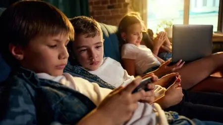 A teenager looks at a smartphone showing social media apps, with the European Union flag in the background.