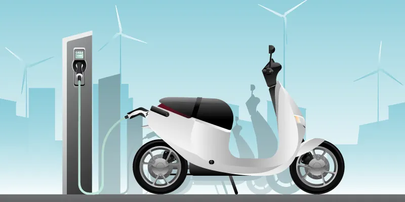 Electric scooters lined up on a production floor at an Indian two-wheeler factory.