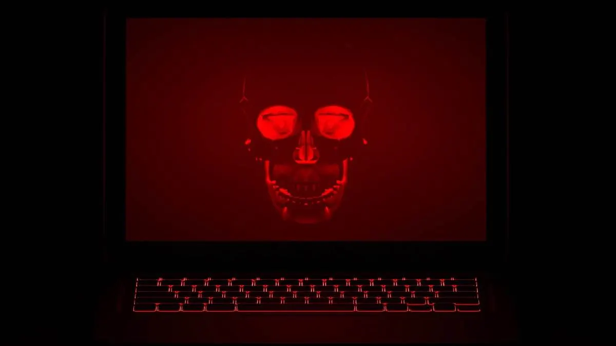 A laptop on a dark desk with a glowing Binance logo and a red security breach warning on screen.