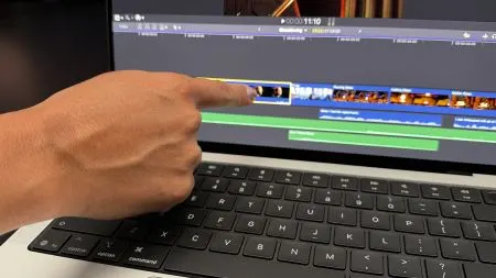 A MacBook Pro with an open lid and a hand touching the display during a hands-on session.