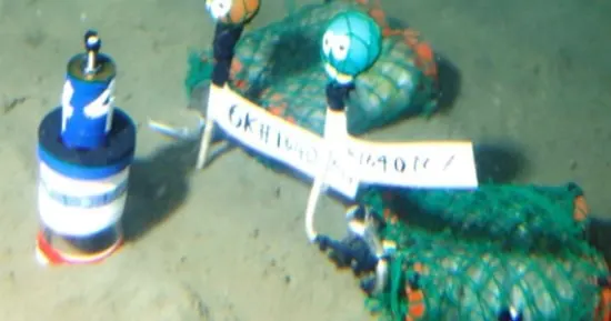 Plastic waste drifting in clear ocean water above the seabed, illustrating marine plastic pollution.