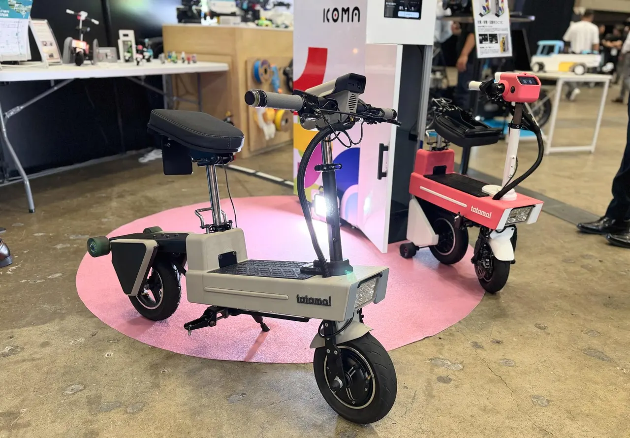 A compact foldable robotic e-bike with a smiling display face on its handlebar, shown at Japan Mobility Show Bizweek 2026.