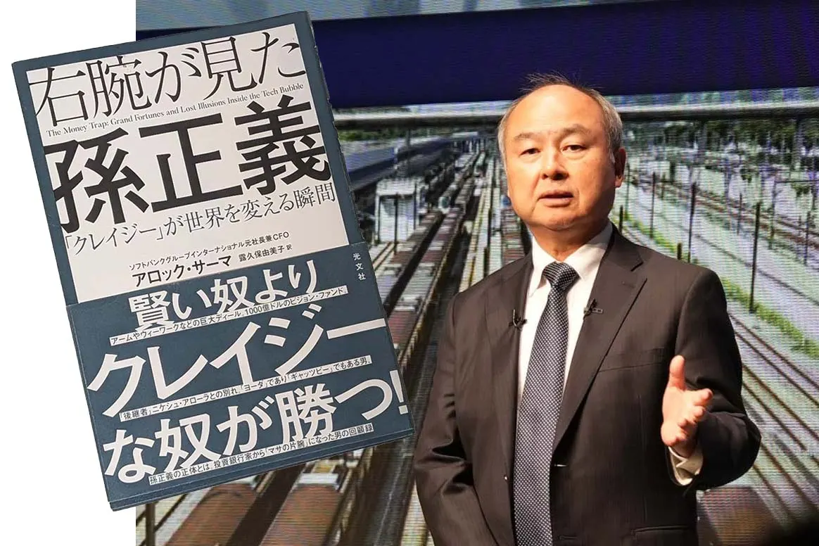 A business book about SoftBank and Masayoshi Son lying on a desk beside a laptop and a cup of coffee.