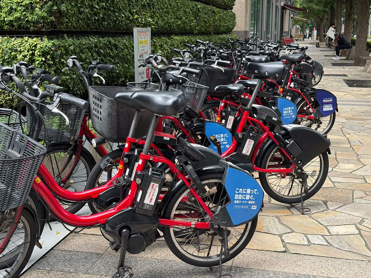Commuters on bicycles riding along a city road near a station in Japan during the morning rush hour.