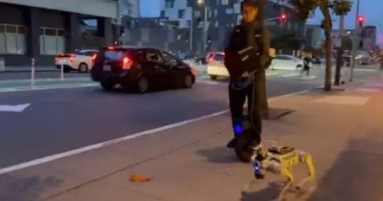 A person walking a four-legged robot dog along a San Francisco street during an outdoor test.